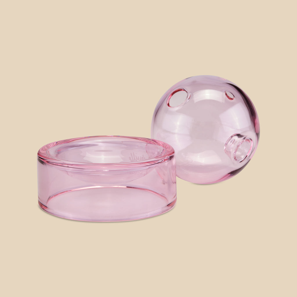 Unser runder One Hitter – die Crystal Ball Pipe aus Glas – liegt neben dem farblich passenden Glasfuß in Pink. (Bild: AURIEY)